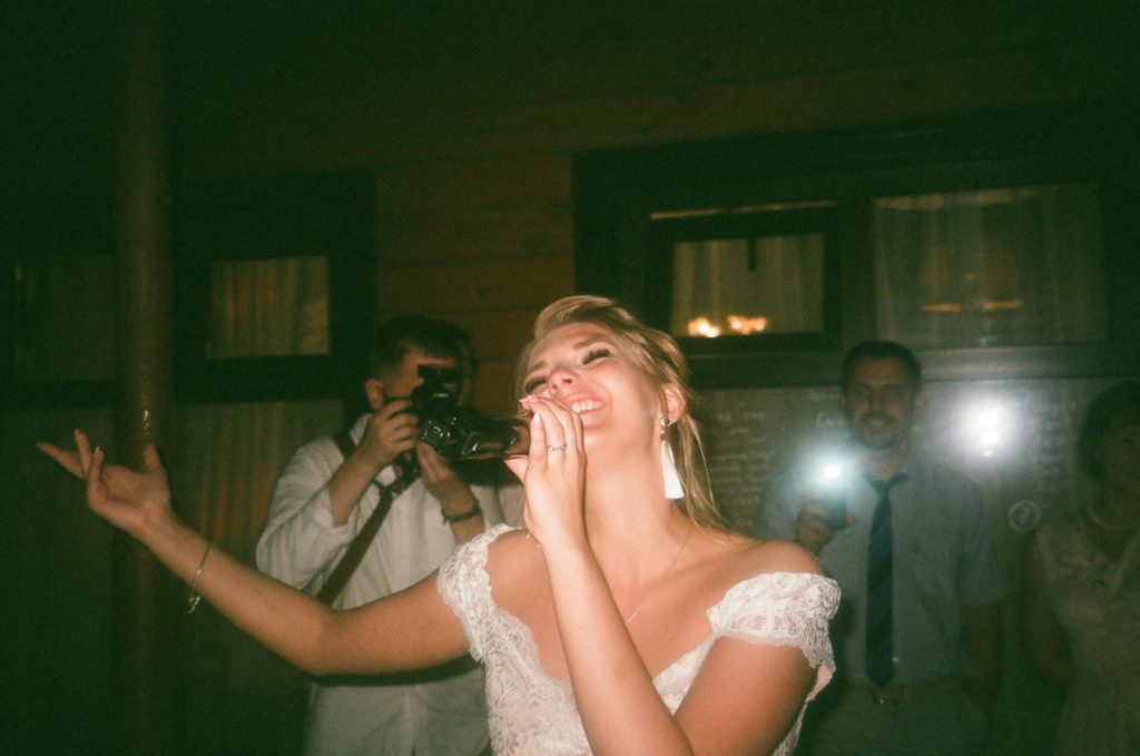 A happy woman singing passionately at a lively indoor event.