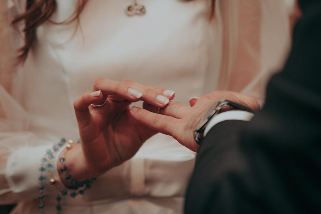 Close-up of hands exchanging wedding rings during an elegant ceremony.
