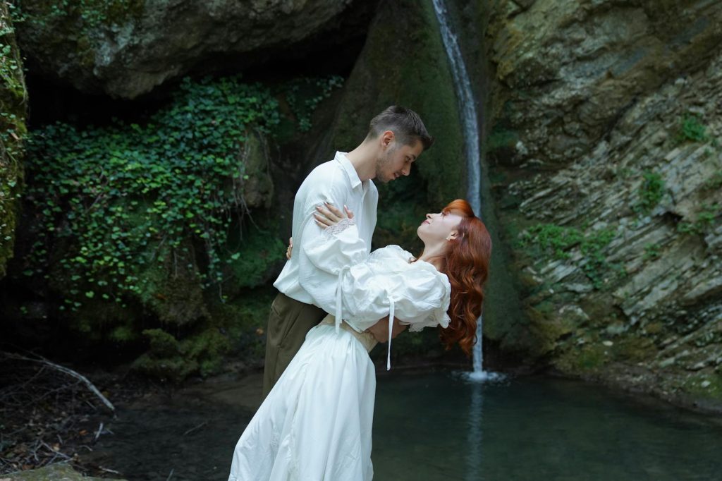 Couple in vintage attire embracing by a waterfall in Istanbul, Turkey.