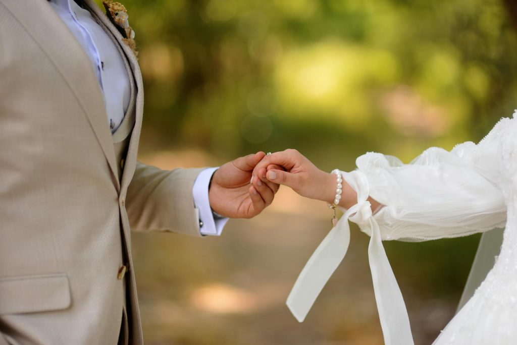 Close-up of a couple holding hands outdoors, symbolizing love and commitment.