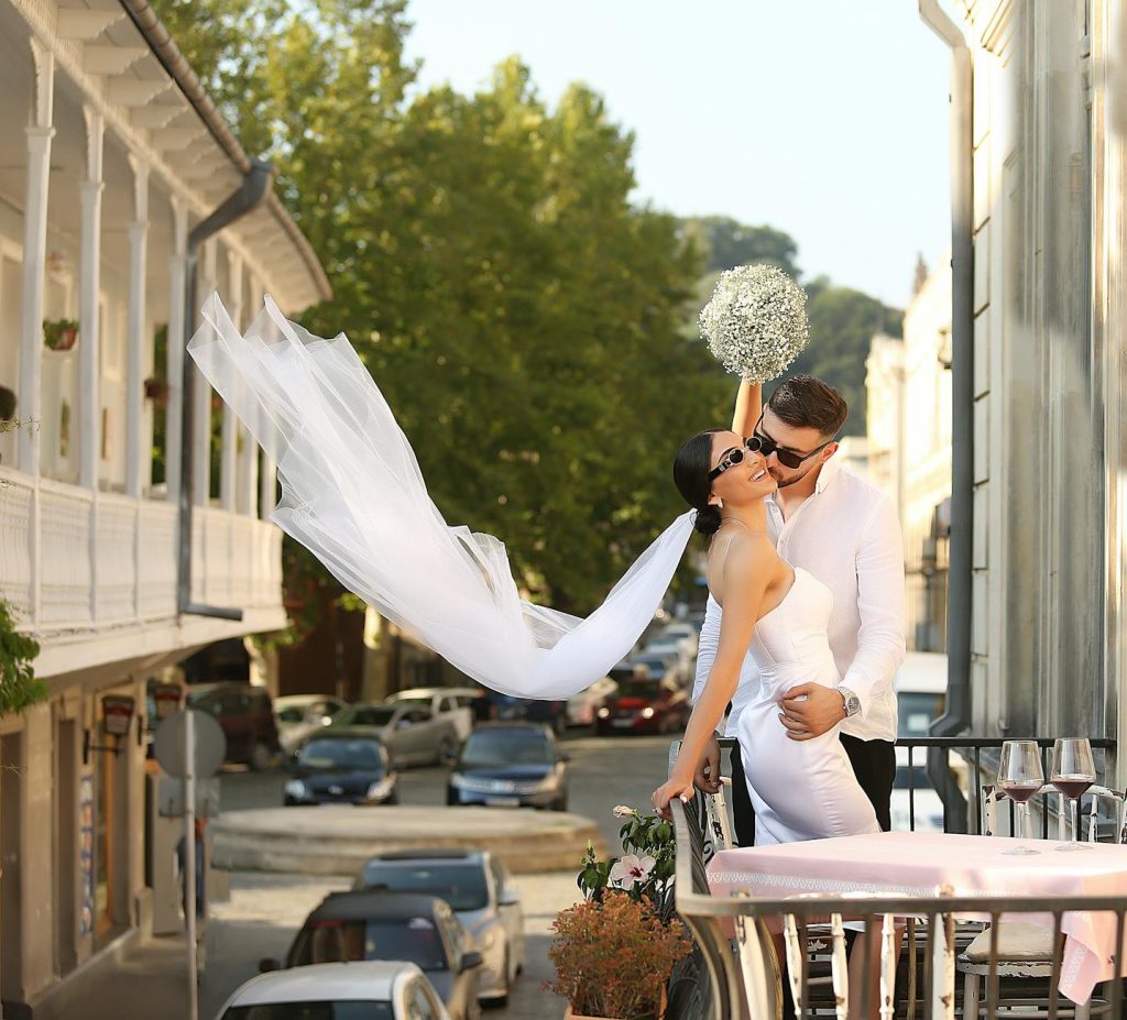 Elegant bride and groom share a romantic kiss on a sunny wedding day in Tbilisi.