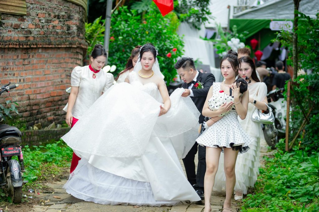 A bride and her entourage in traditional Vietnamese attire at an outdoor wedding in Hanoi, Vietnam.