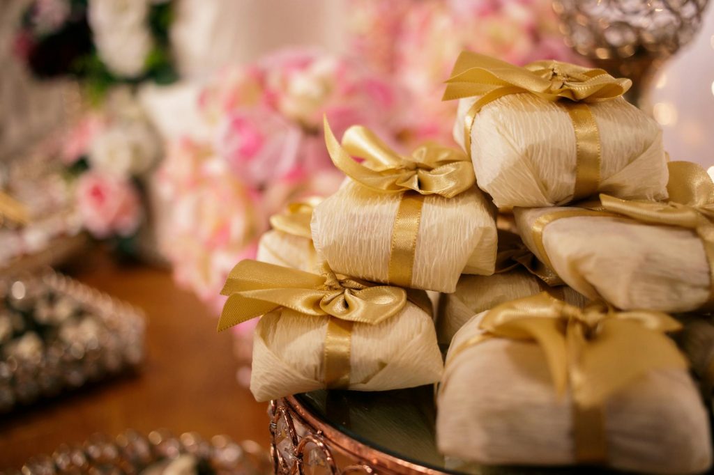 Beautifully wrapped Brazilian wedding favors with golden ribbons on a decorated table.
