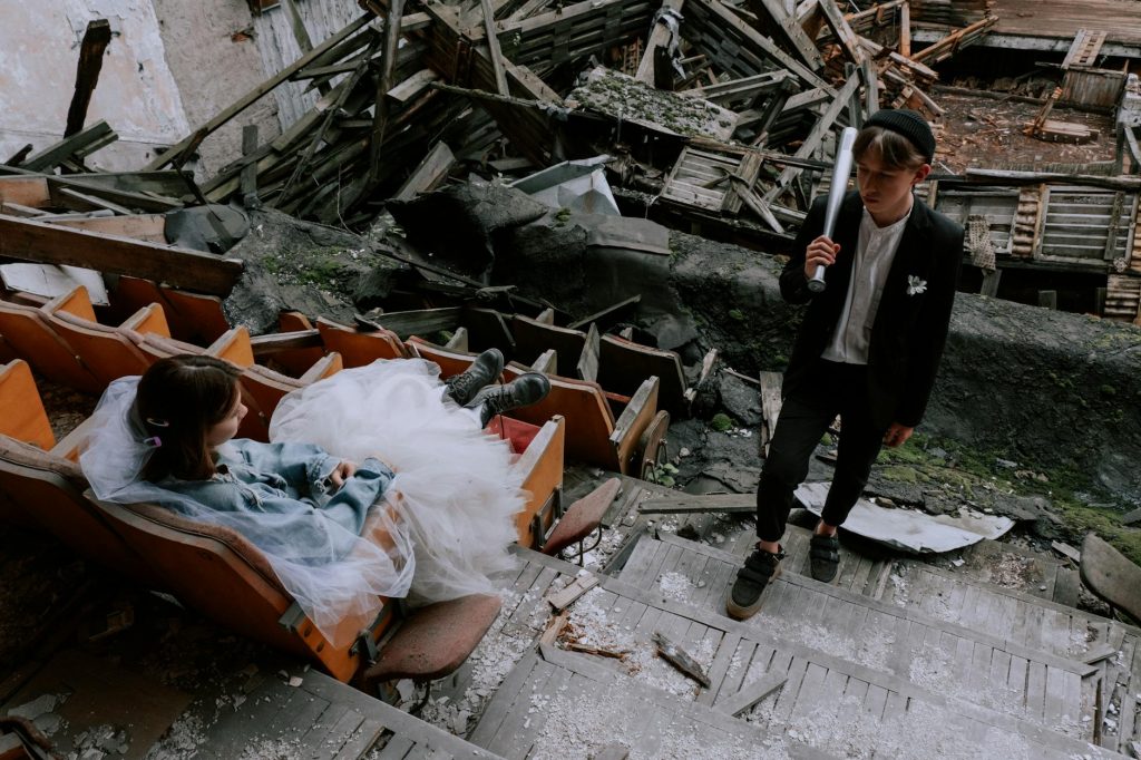 A unique bridal couple poses creatively in a demolished theater setting.