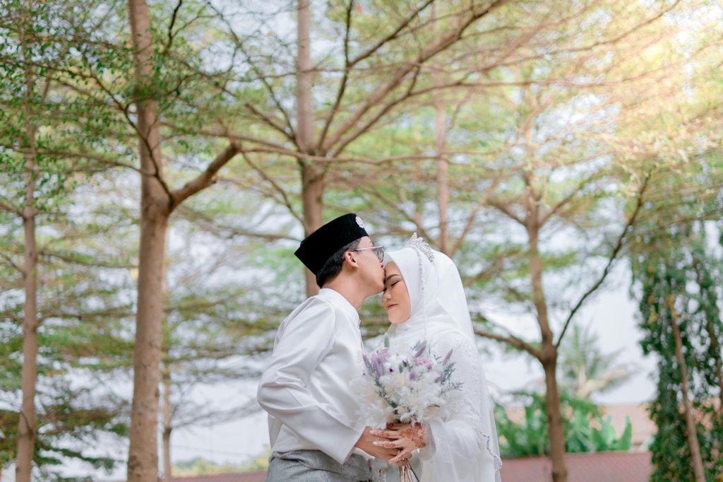Elegant couple in traditional wedding attire under trees in Bandung.