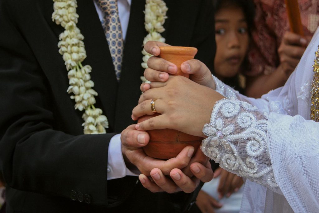 Close-up of a Sundanese wedding ceremony with clay jug ritual in West Java.