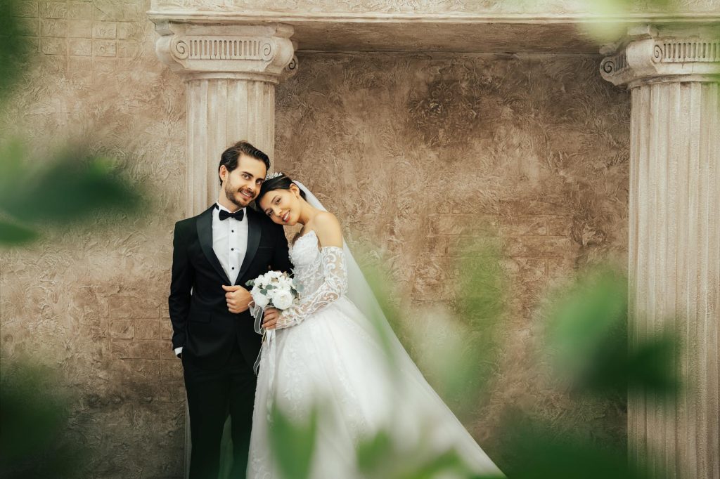 A romantic wedding portrait of a couple posing by classical columns in Antalya, Türkiye.