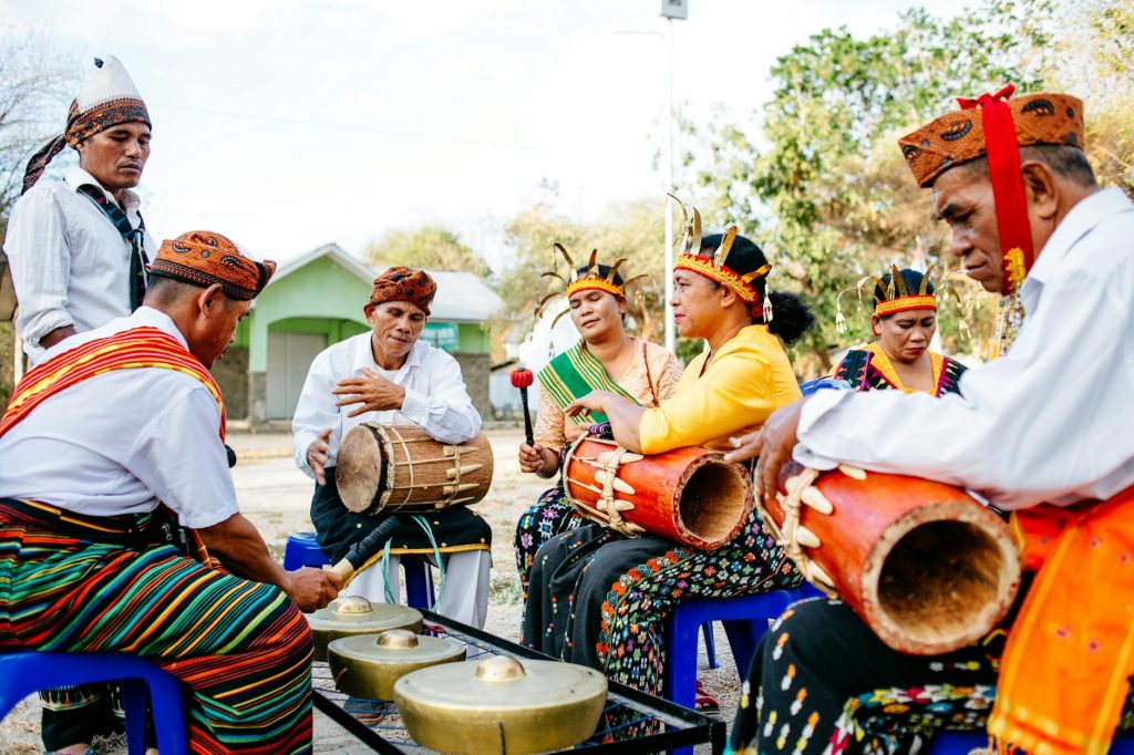 A group of musicians in traditional attire play instruments at a festival in Indonesia.