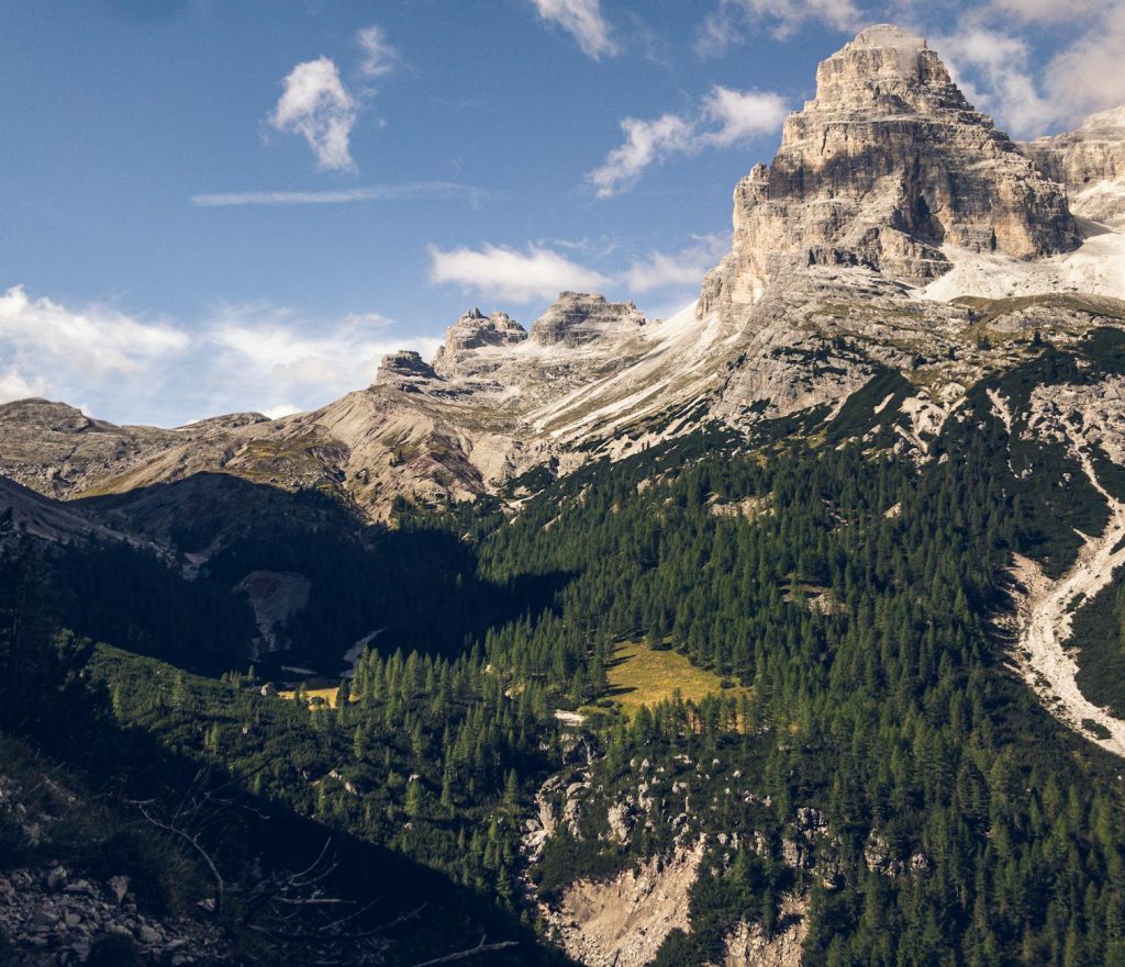 Scenic landscape of the Dolomites mountains with lush forests under clear blue sky.