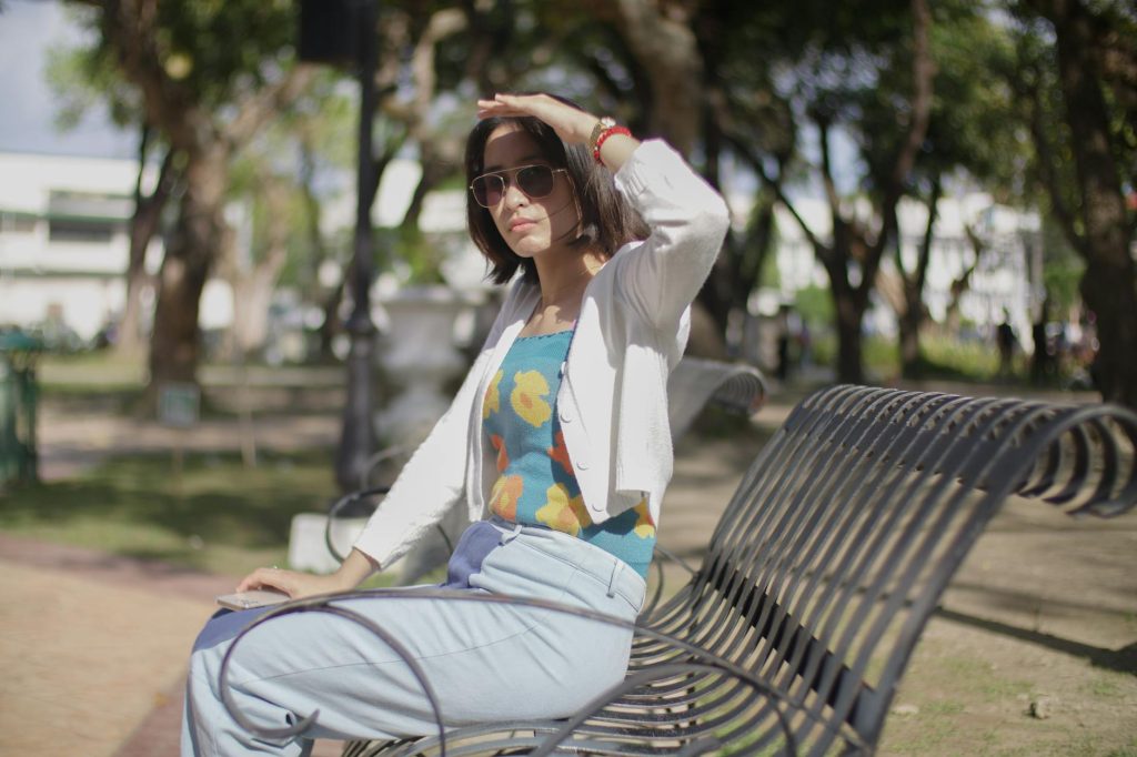 Woman enjoying a sunny day on a bench at a park in Iloilo City, Philippines.