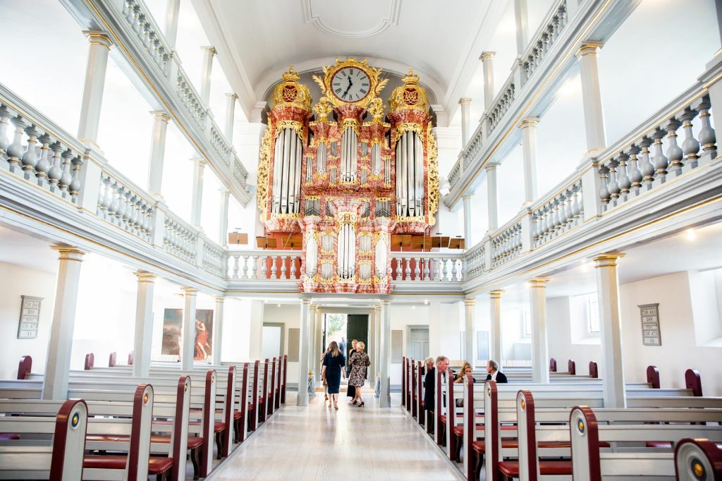 Bright church interior featuring ornate organ and people, perfect for architectural insights.