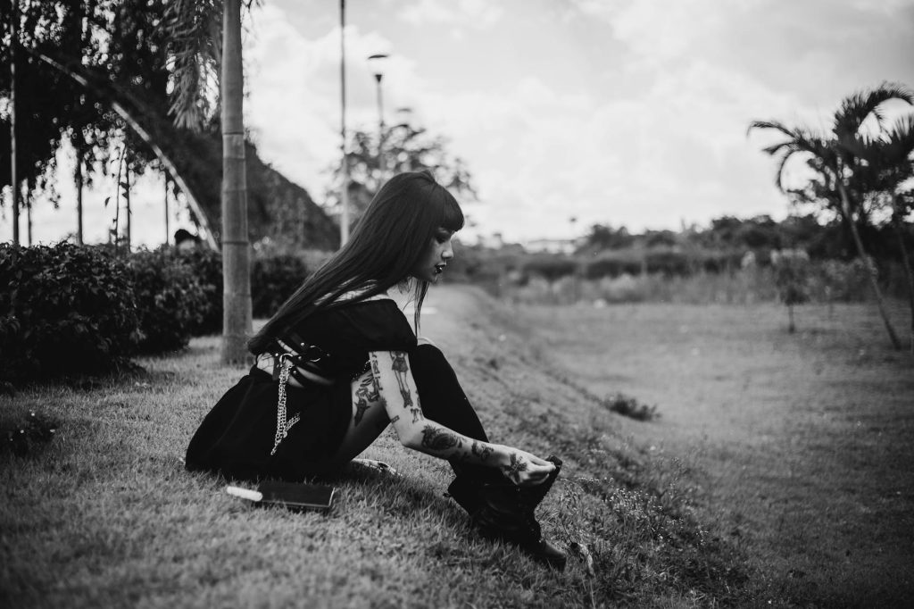 Contemplative woman sitting in a serene outdoor environment, captured in black and white.