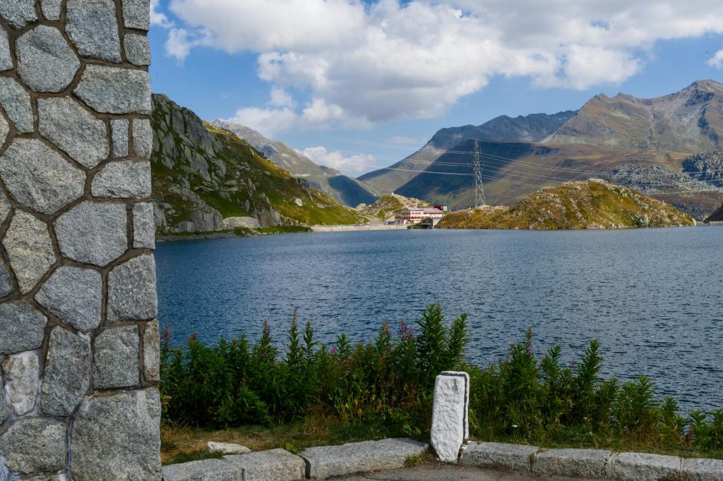 A stunning view of a serene alpine lake surrounded by mountains and blue skies.