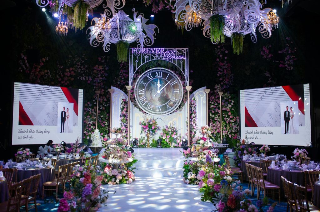 Luxurious wedding hall with ornate floral decorations and large clock centerpiece.