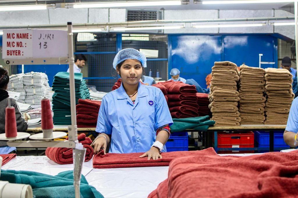 A textile worker in a factory folds towels, showcasing blue-collar work and production efficiency.