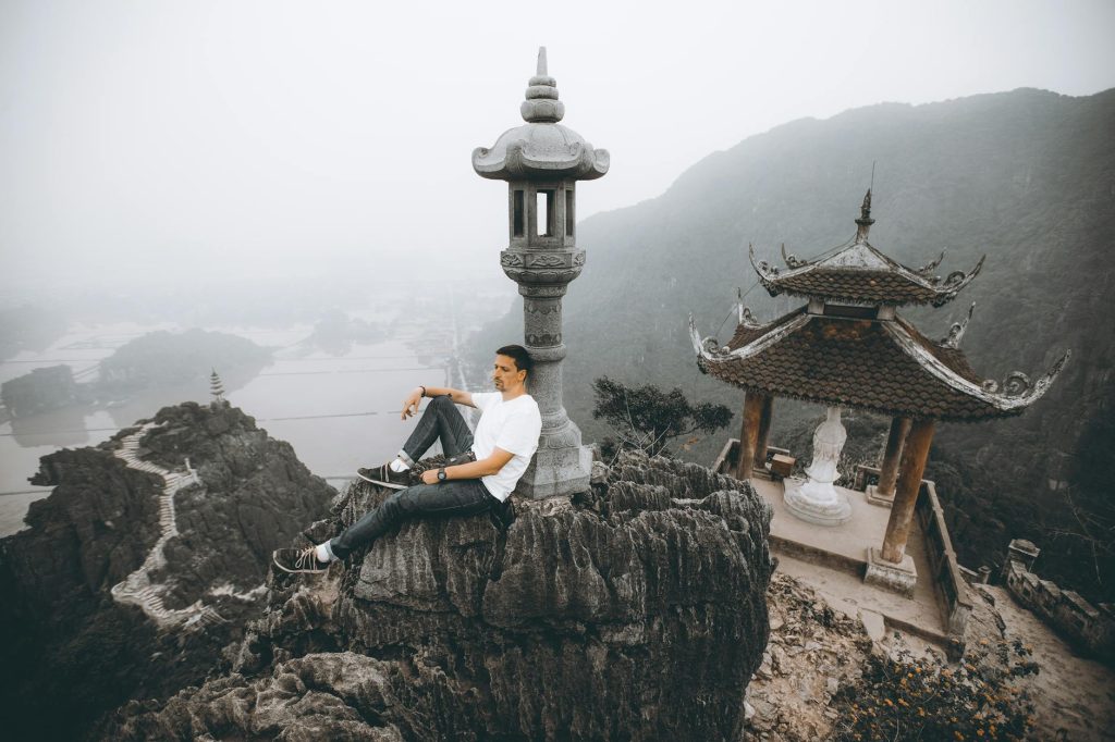 A man sitting on a rock at Mua Cave viewpoint, overlooking Ninh Bình's stunning landscapes.