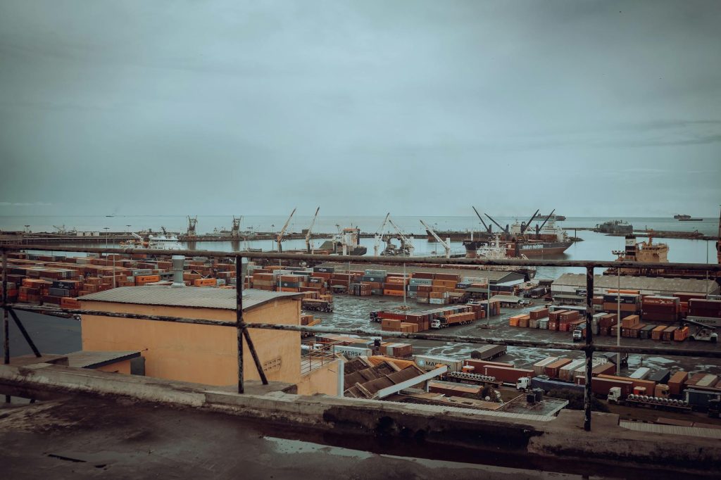 View of Tema Port in Ghana featuring shipping containers and cranes under a cloudy sky.