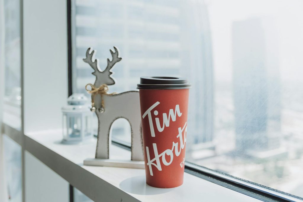 Tim Hortons coffee cup with festive reindeer decor by a window in Dubai.