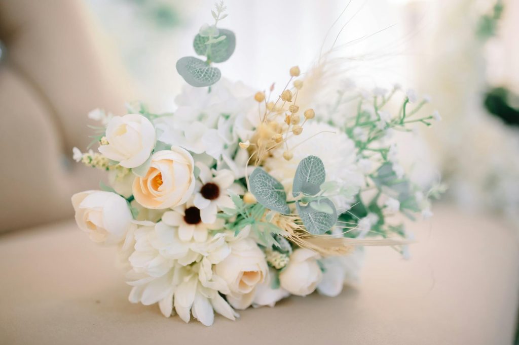 Susunan bunga hias bercahaya yang diletakkan di permukaan krem dalam ruangan terang dengan latar belakang buram.