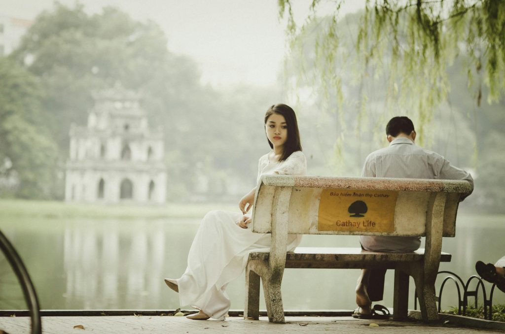 A couple sitting on a bench near Hanoi's iconic Turtle Tower, seemingly deep in thought.
