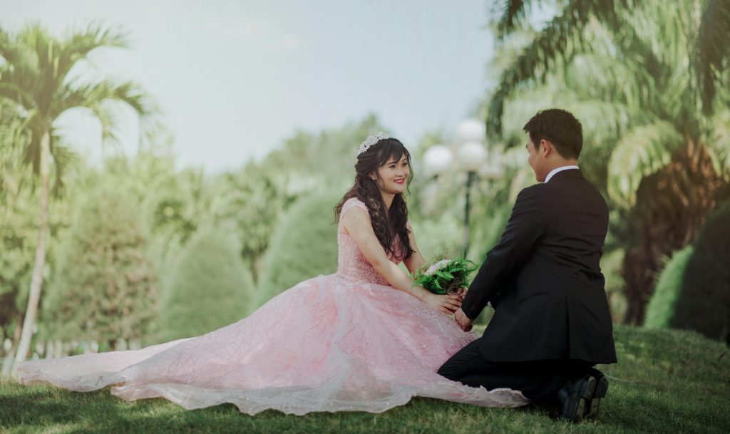 A romantic outdoor wedding scene with a bride and groom in a lush green park.
