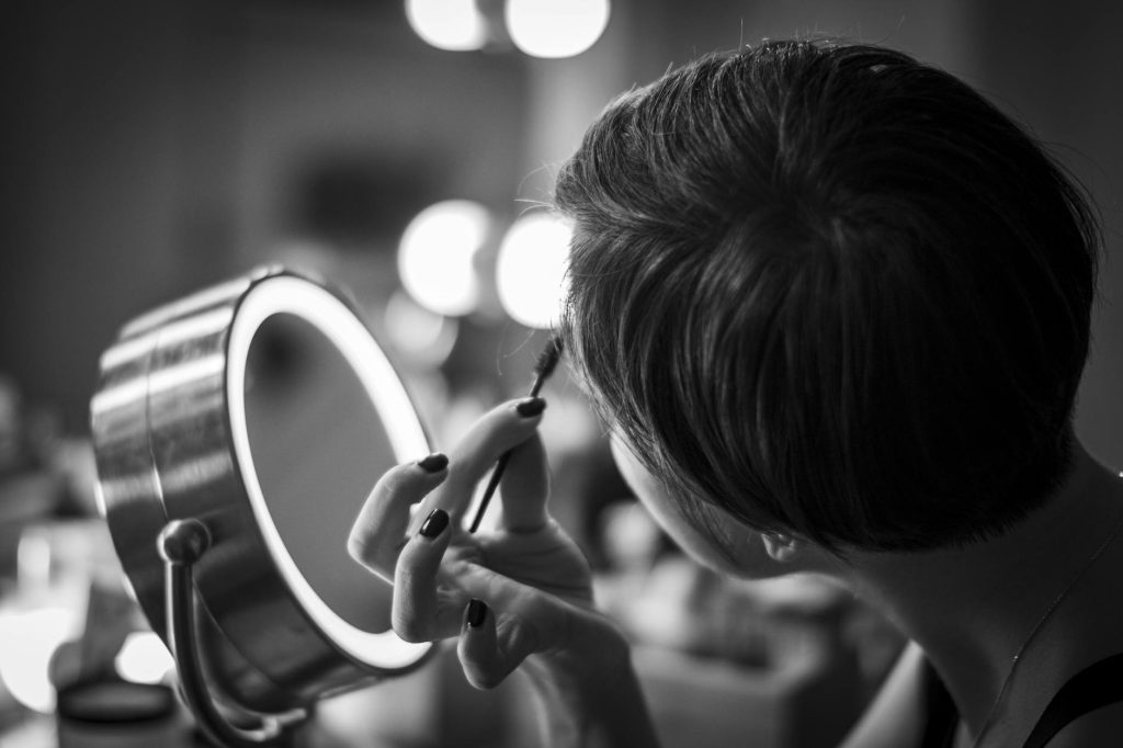 A woman applying makeup using a ring light for perfect lighting in a detailed close-up.