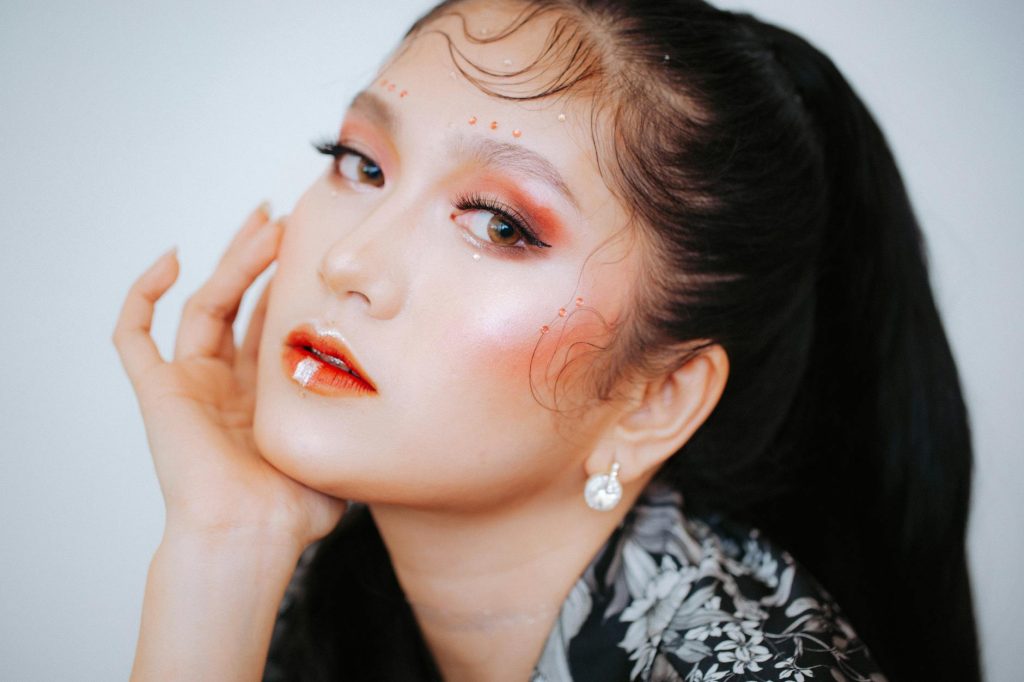 A stunning close-up portrait featuring vibrant and artistic makeup highlighting facial features.