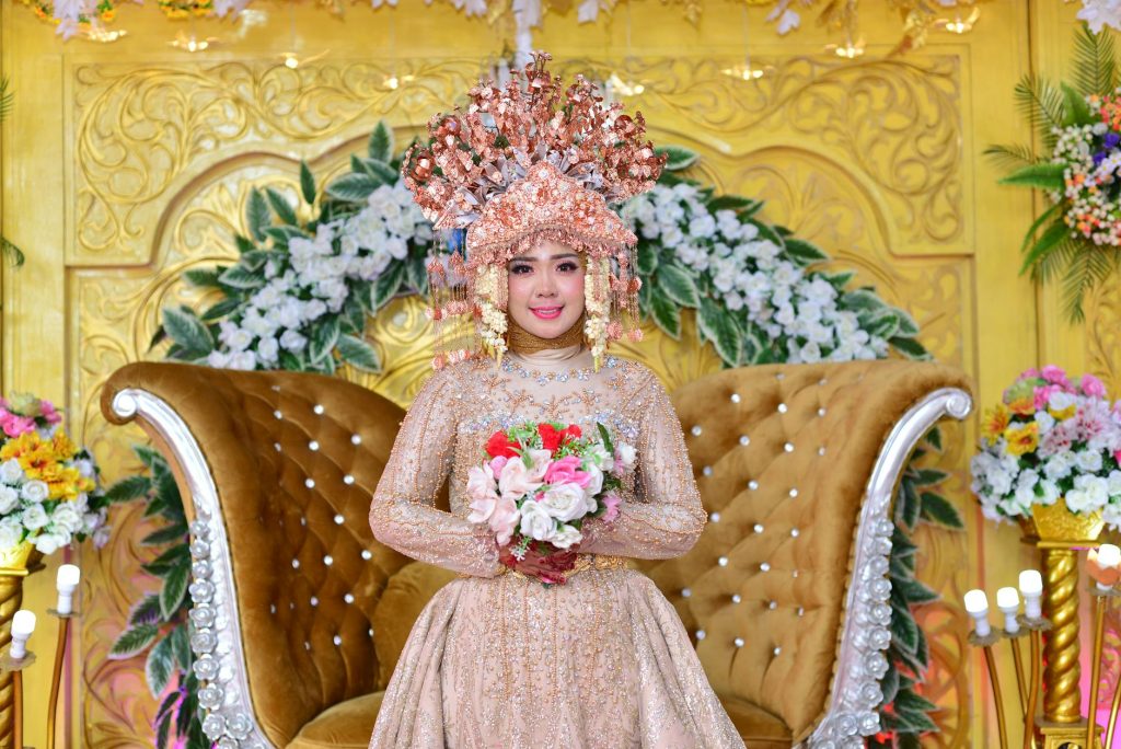 Bride in beautiful traditional attire with elaborate headdress holding a bouquet.