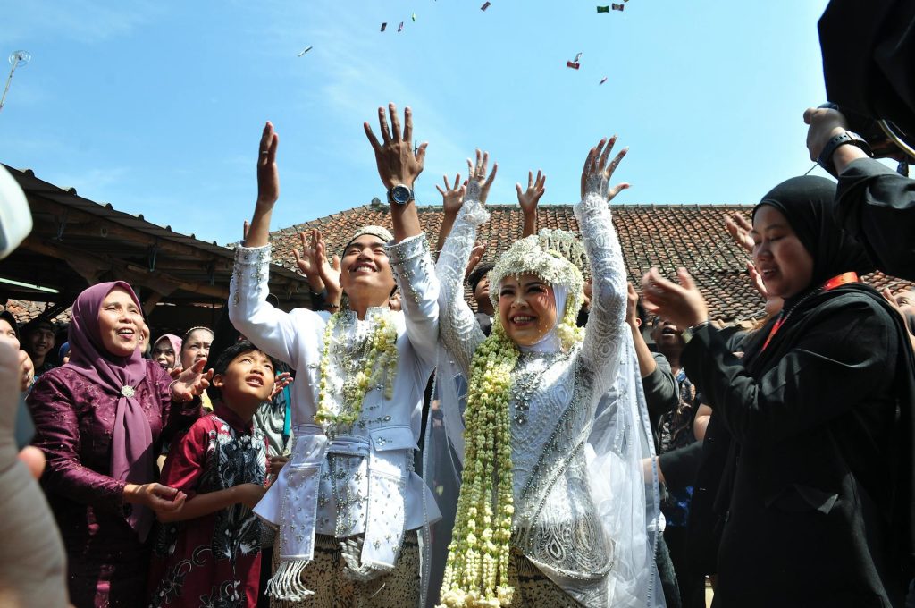 Traditional Sundanese wedding in Bandung, West Java, featuring happy couple and guests celebrating outdoors.