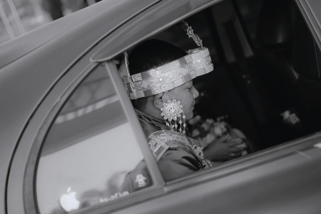 A groom in traditional Makassar wedding attire seated in a car, reflecting cultural heritage.