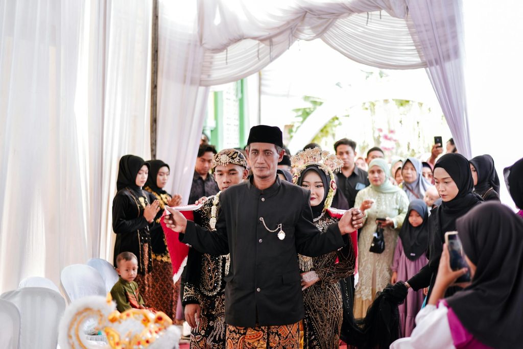 A vibrant gathering of people in traditional Javanese attire during a wedding ceremony.