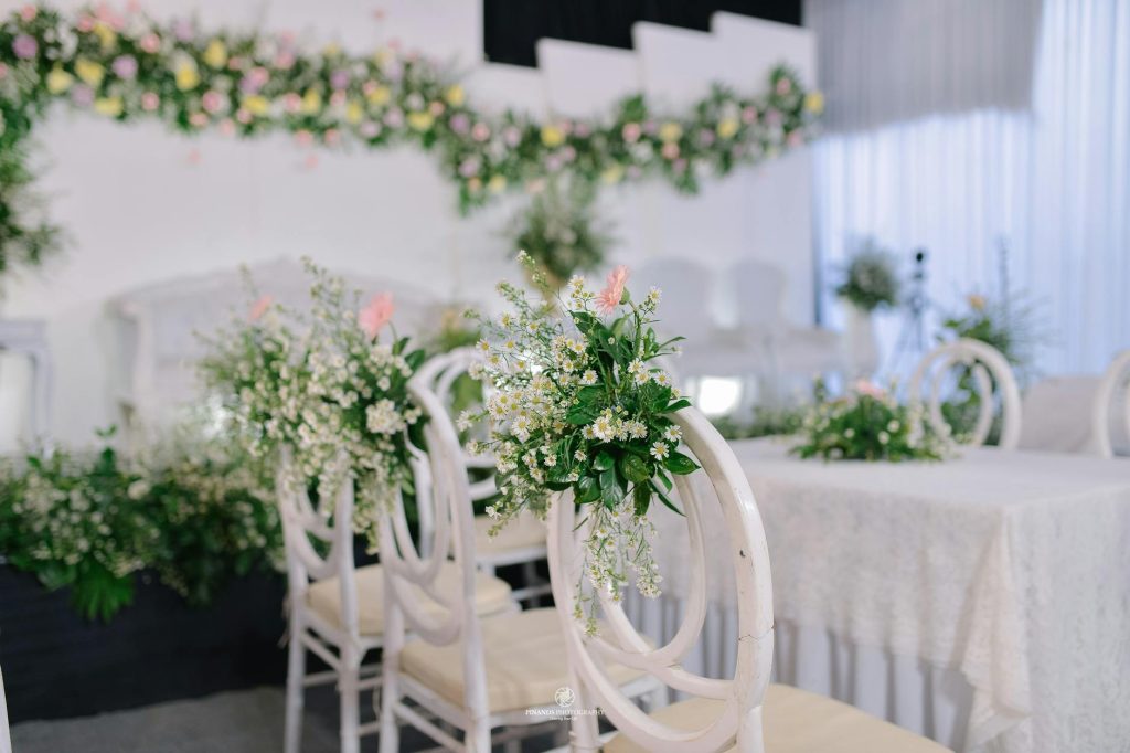 Elegant wedding venue featuring white chairs and lush floral arrangements, perfect for memorable events.